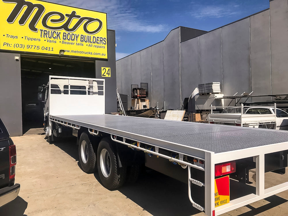 Custom heavy-duty flat tray truck body with raised side combings, swept rear and 5mm floor, built by Metro Truck Body Builders Melbourne.